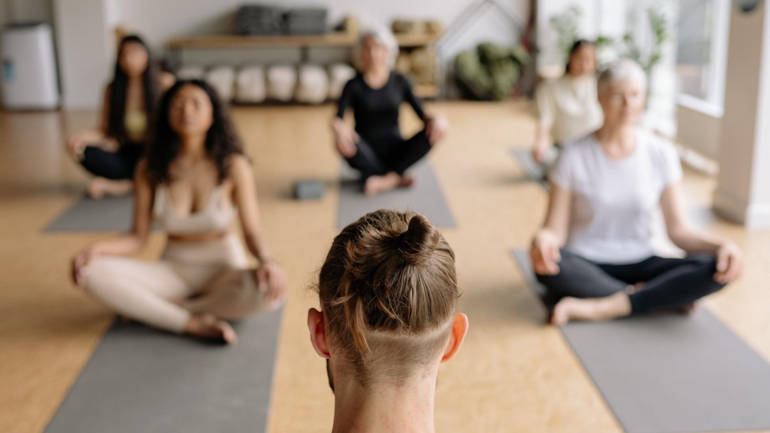 4 people meditating in a meditation class, with a male instructor in front of them