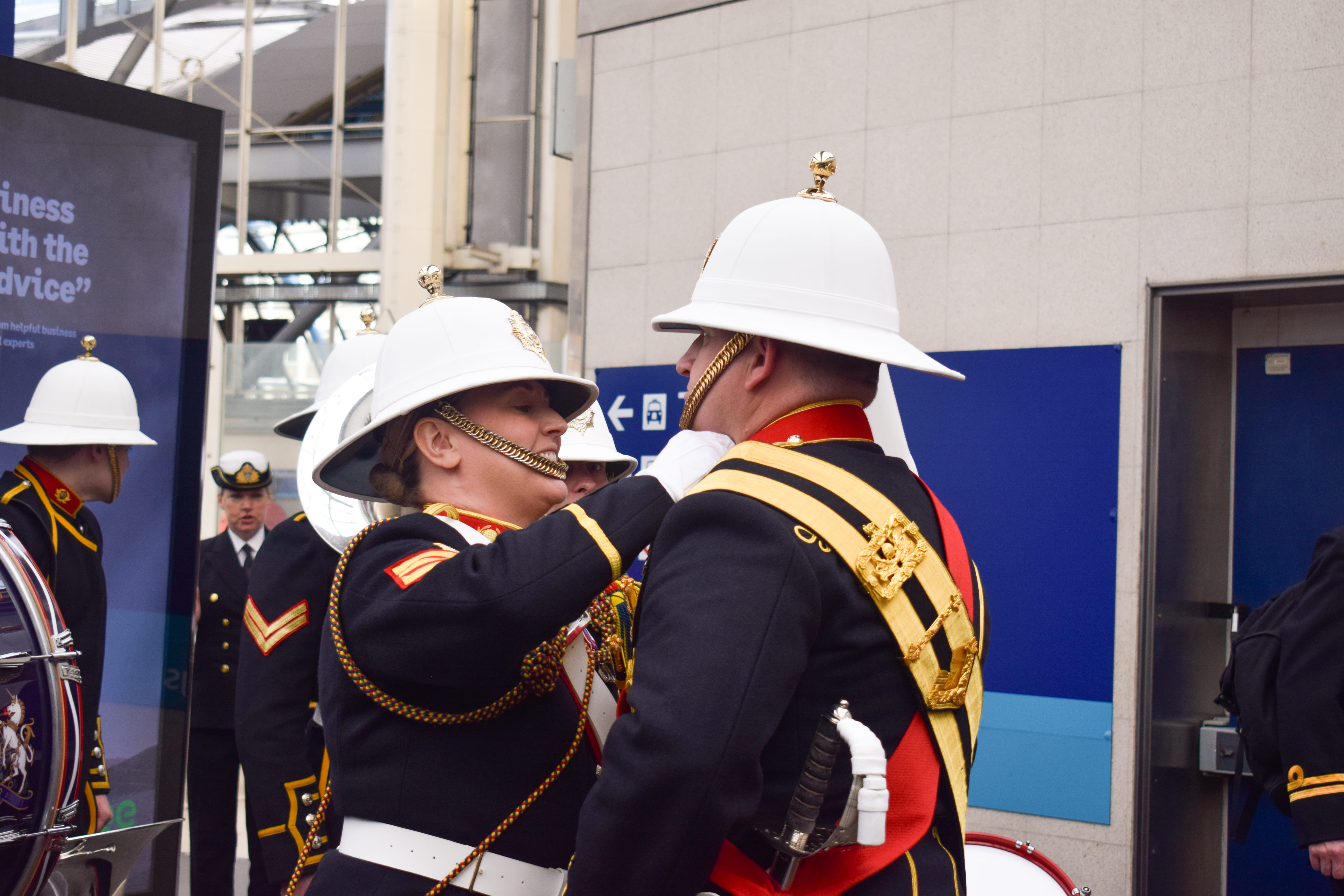 One member of a Royal Marines band on the platform at Waterloo adjusting another's collar