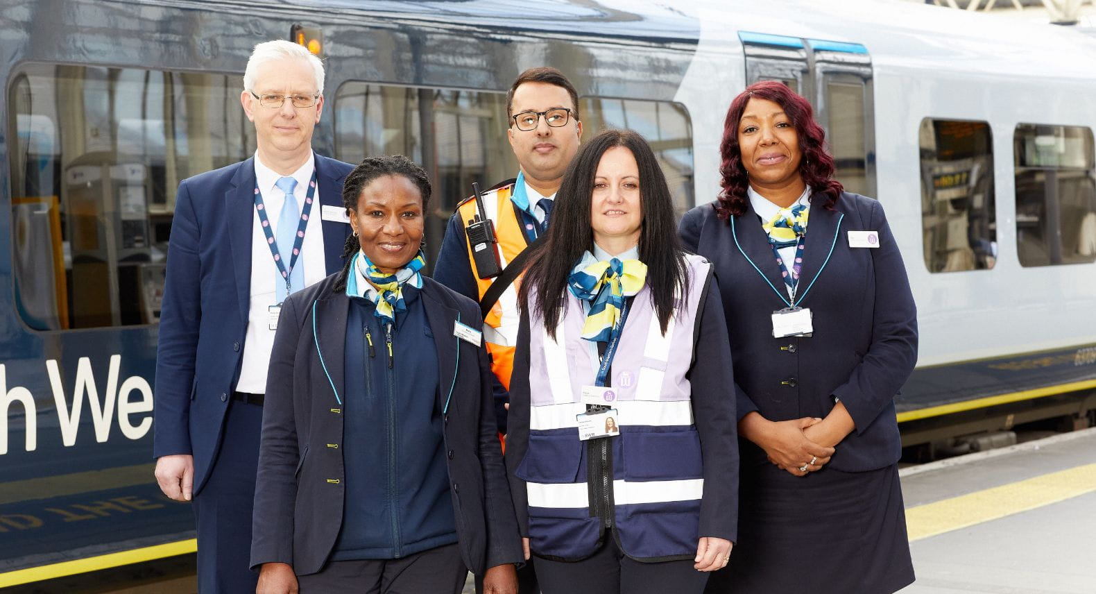 Group of 5 SWR colleagues in uniform standing on the platform in front of a train