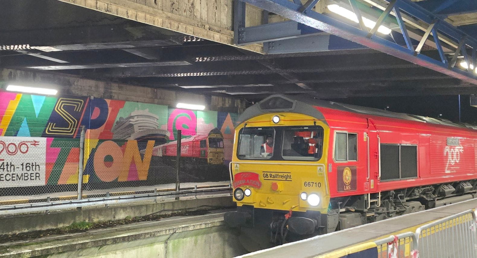 Red locomotive in front of a brightly coloured mural