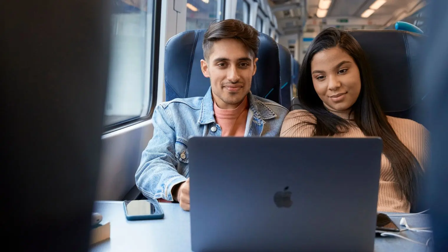 Couple on train looking at a laptop