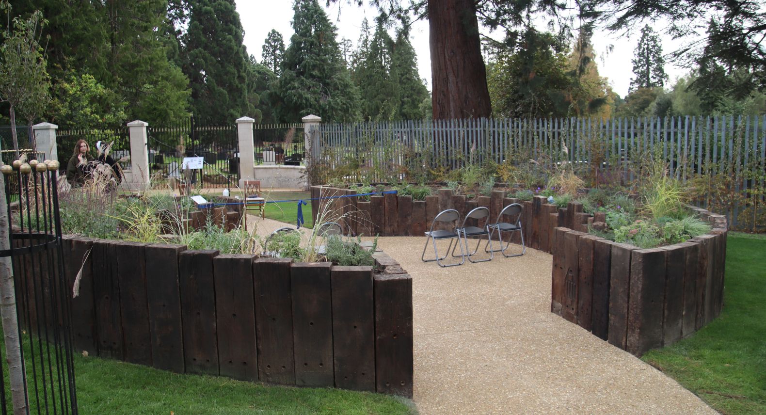 View of two semi circles of planters made from railway sleepers in a garden setting