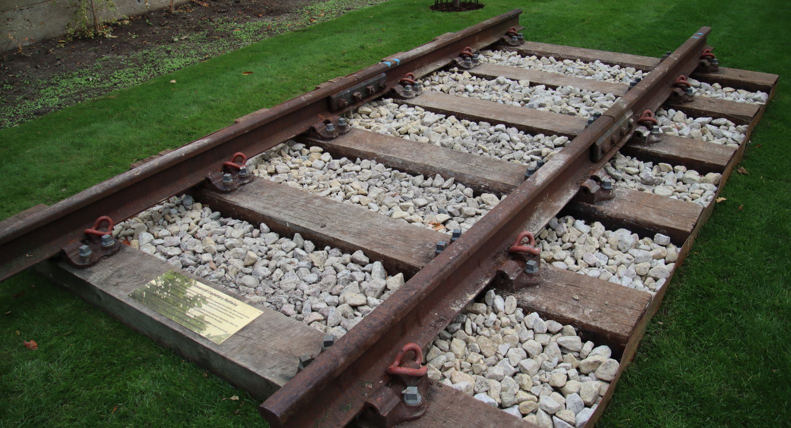 Section of railway track with a brass plaque laid in a reflective garden