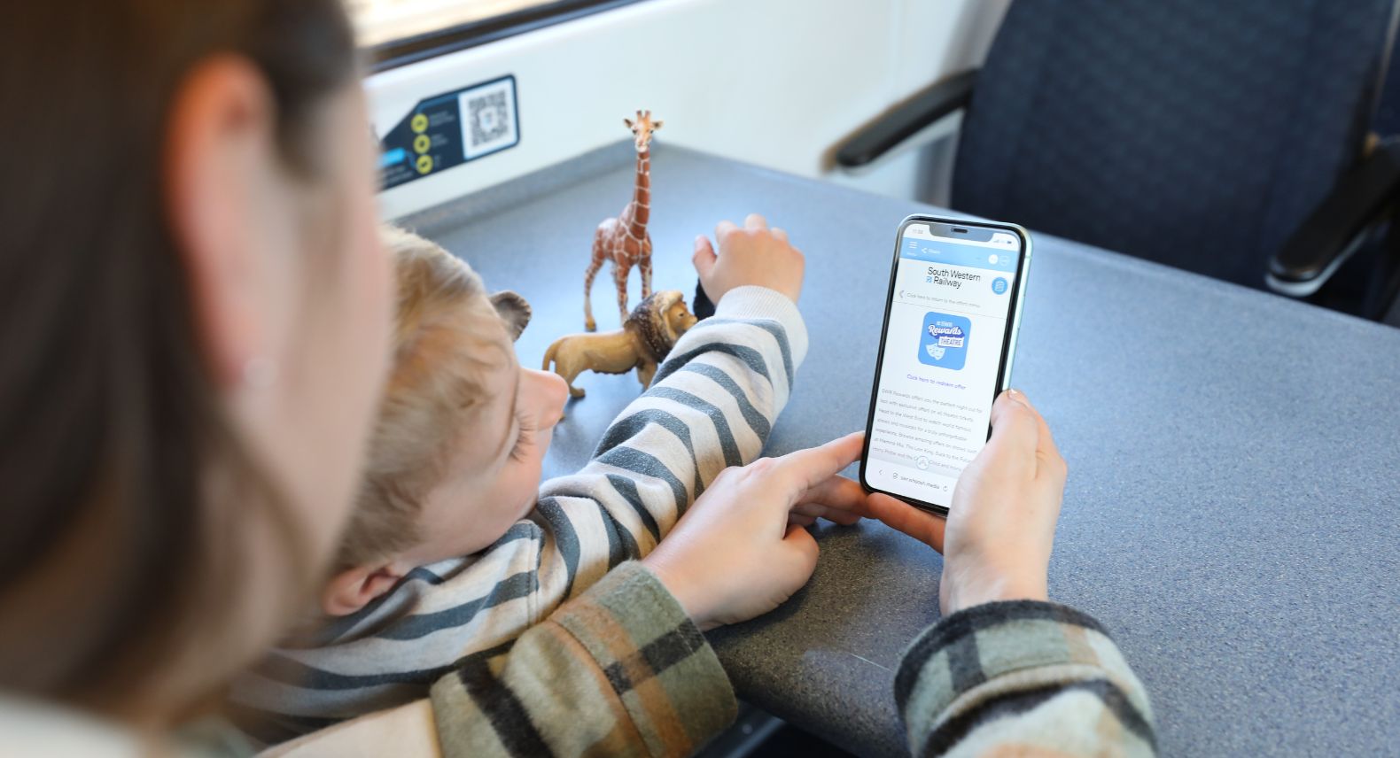 Woman and child at table on train looking at mobile phone