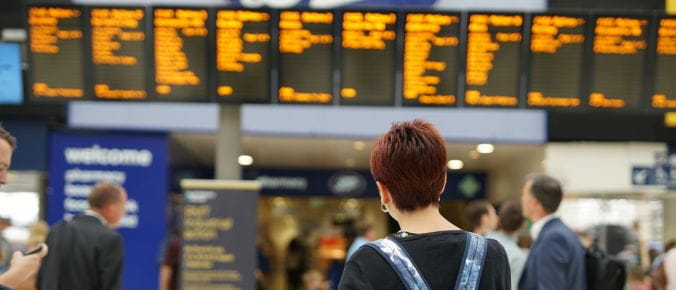 Customer looking at the departure boards at London Waterloo train station - South Western Railway