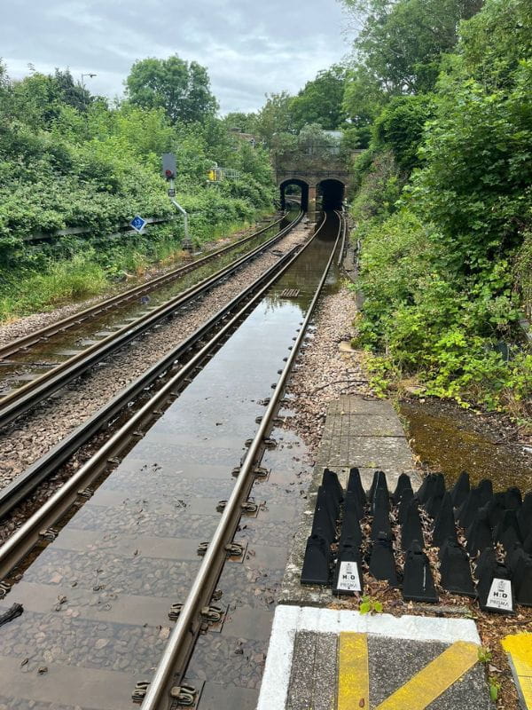 A South Western Railway train that has stopped on the approach to Fullerton Tunnel. Smoke from the electric third rail which was submerged in floodwater can be seen by the tunnel entrance 