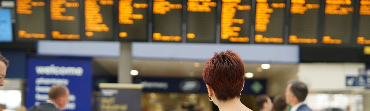 Customer at London Waterloo train station looking at departure boards
