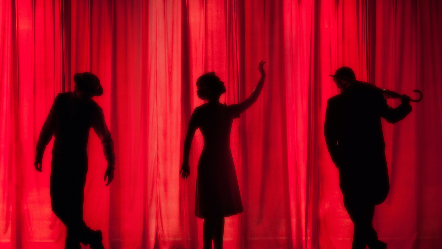 Image of 3 people's shadows behind a curtain on a theatre stage