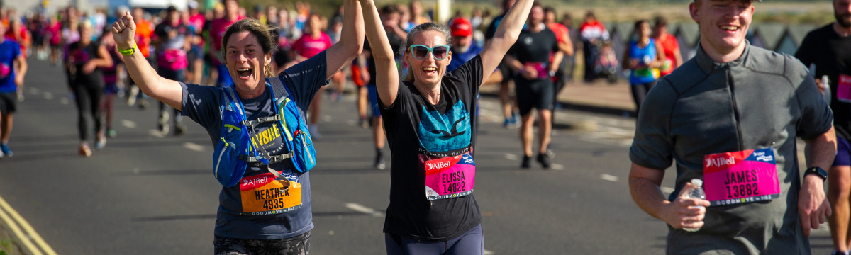 Runners celebrating mid‑race, holding hands and raising arms in excitement.