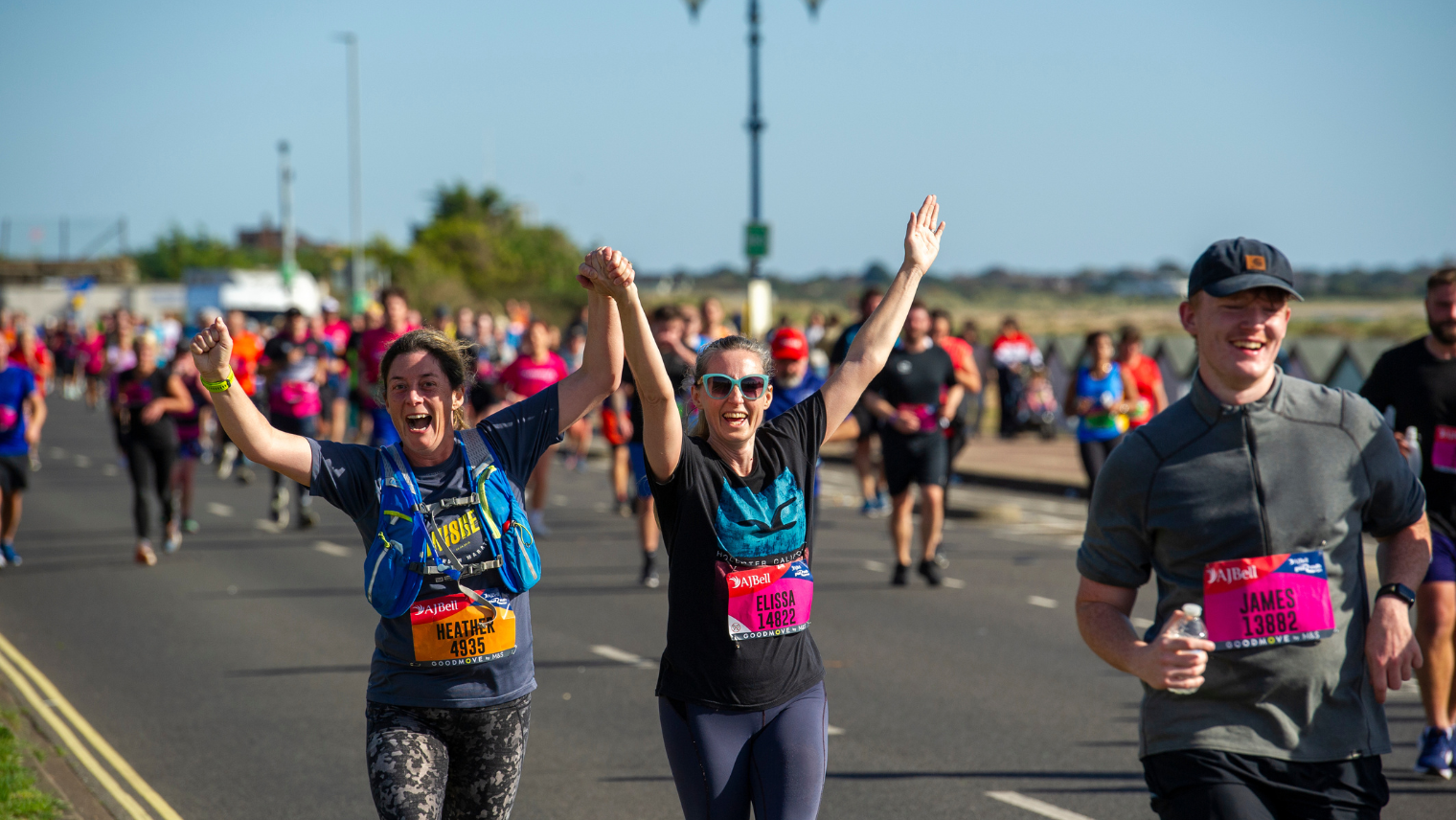 Runners celebrating mid‑race, holding hands and raising arms in excitement.