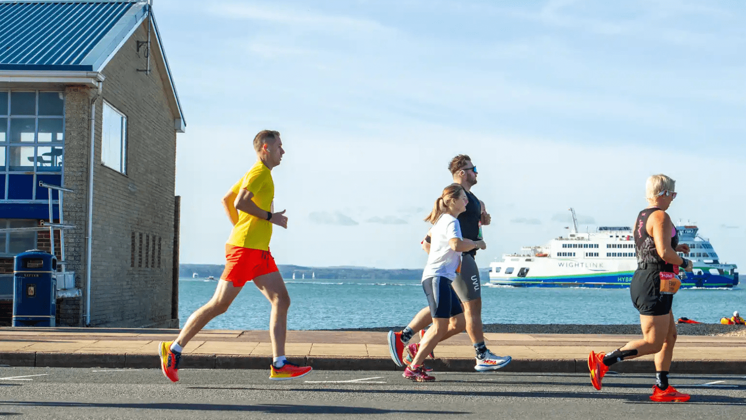 Runners along the waterfront, with a Wightlink ferry visible in the background.