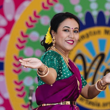 Dancer in vibrant sari performing traditional Indian dance against a colourful “Mela” festival backdrop