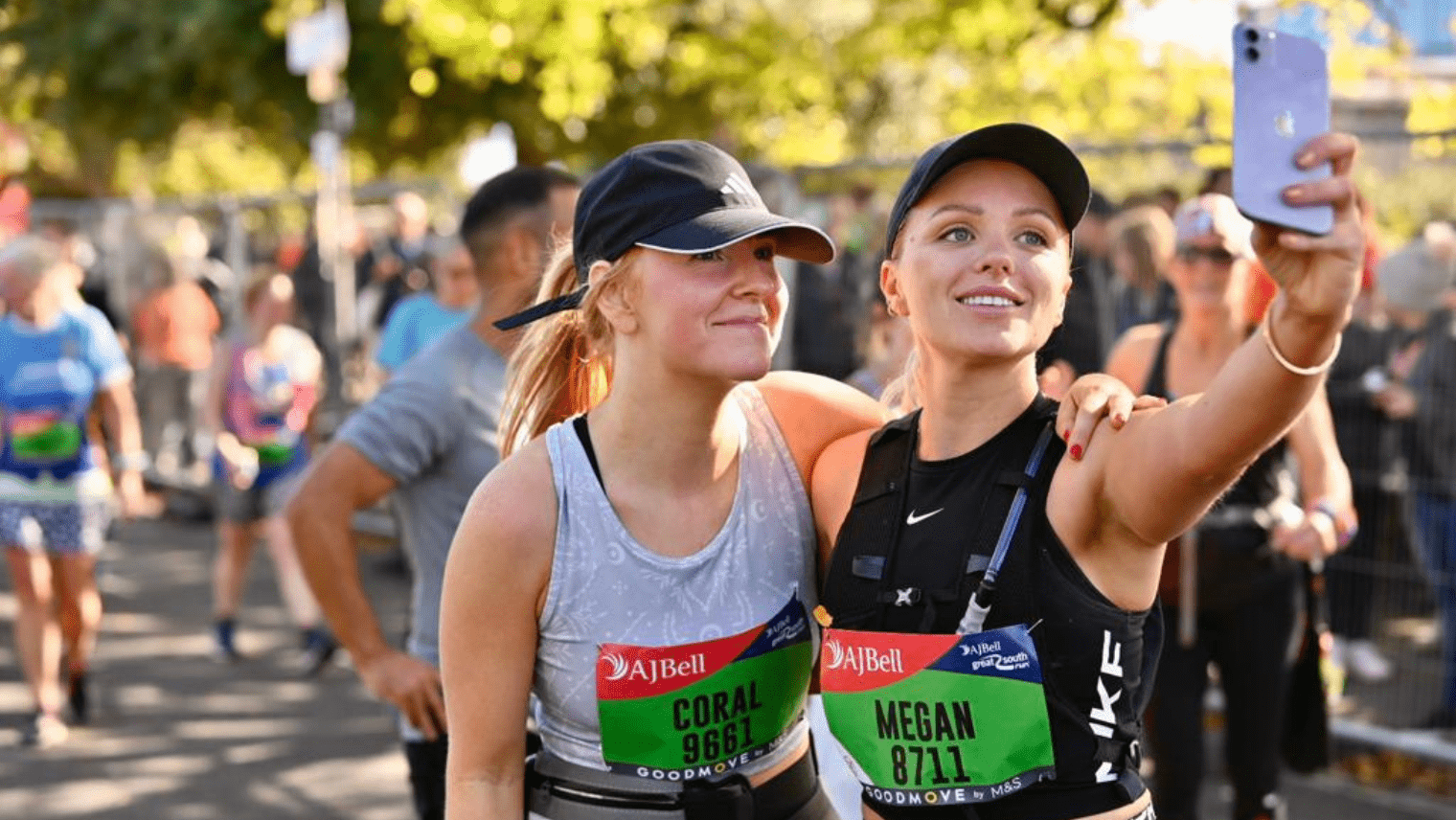 Two runners taking a selfie after finishing a race, smiling and wearing numbered bibs.