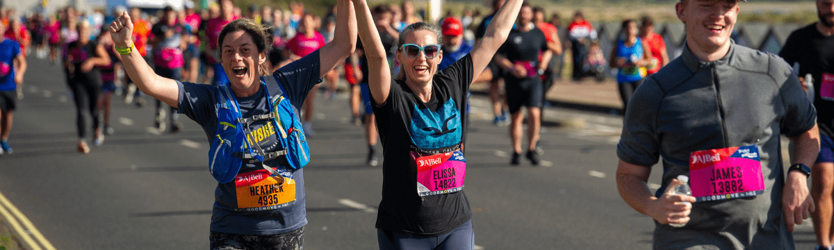 Runners celebrating mid‑race, holding hands and raising arms in excitement.