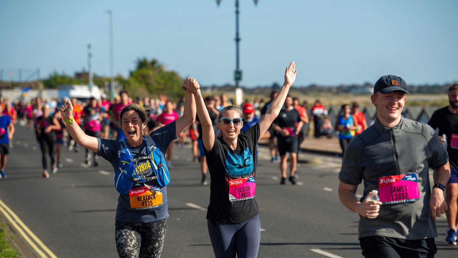 Runners celebrating mid‑race, holding hands and raising arms in excitement.