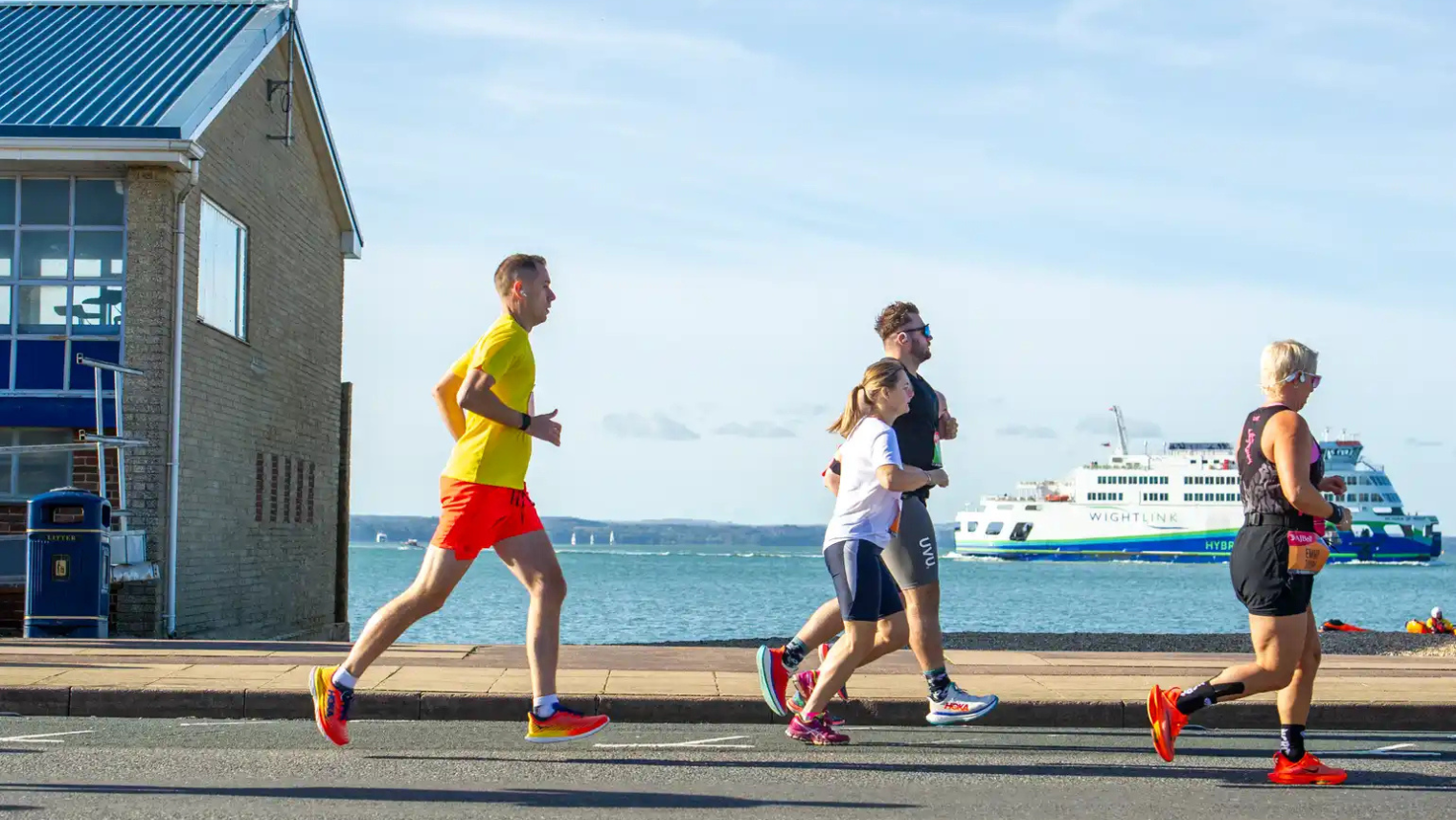 Runners along the waterfront, with a Wightlink ferry visible in the background.