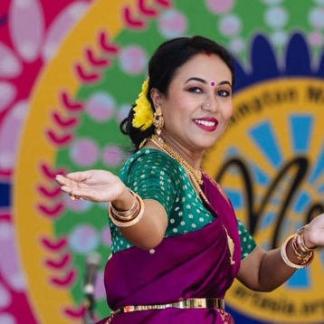 Dancer in vibrant sari performing traditional Indian dance against a colourful “Mela” festival backdrop