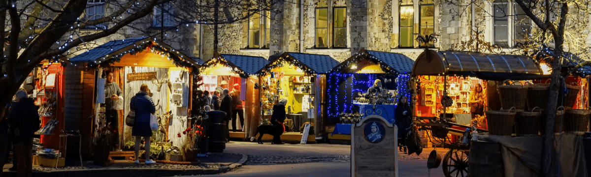 Christmas market stalls by night in front of Winchester cathedral