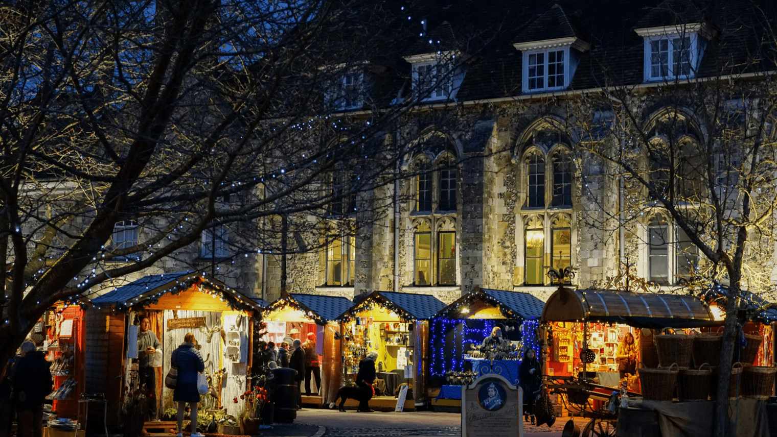 Christmas market stalls by night in front of Winchester cathedral