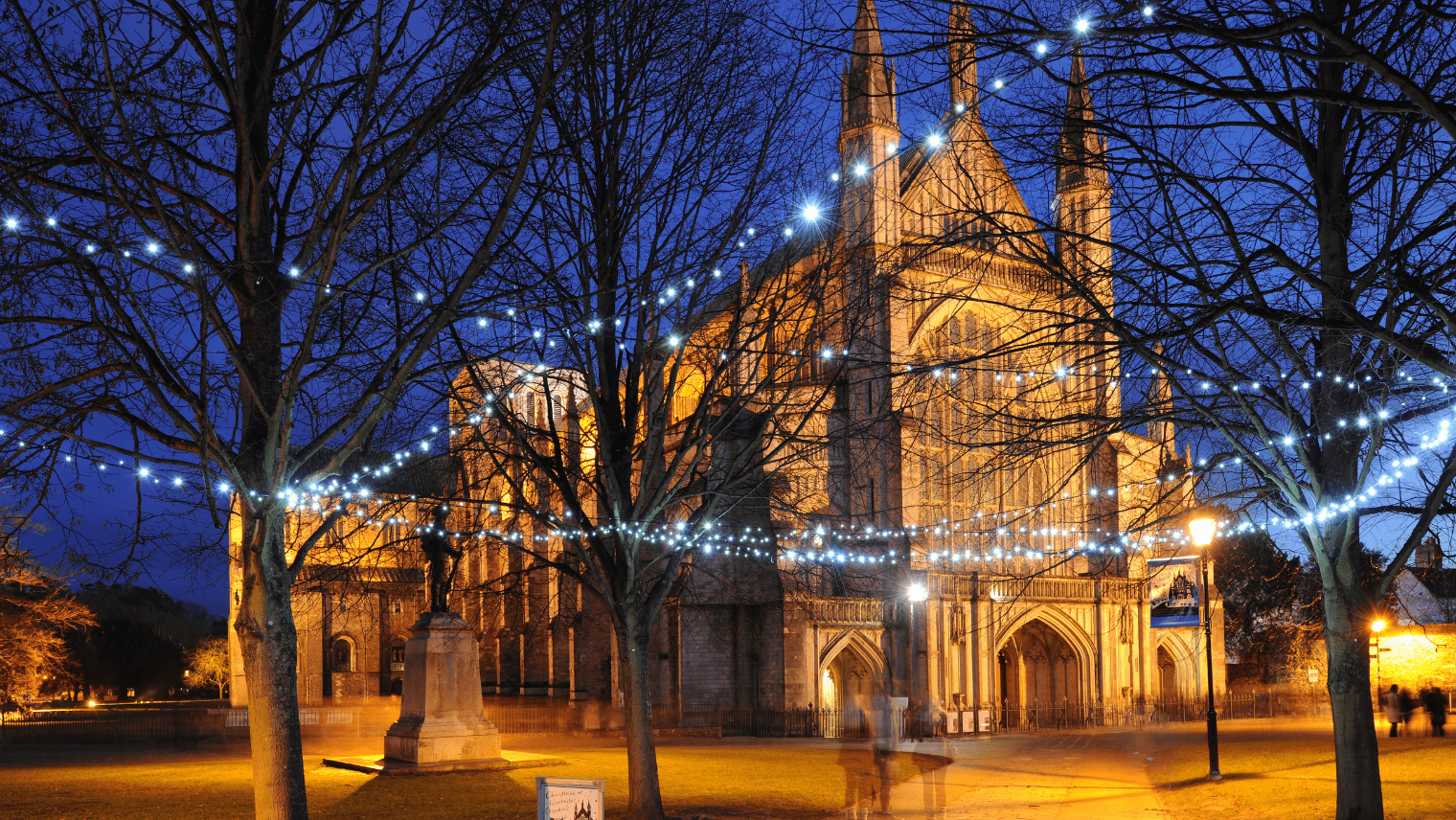 Outside of Winchester cathedral by night with string lights