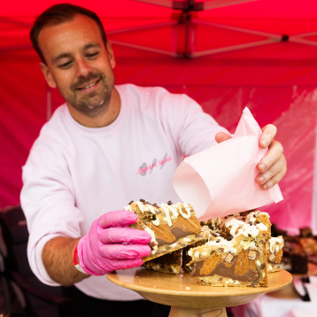  a man plating a cake up on a cake stand 