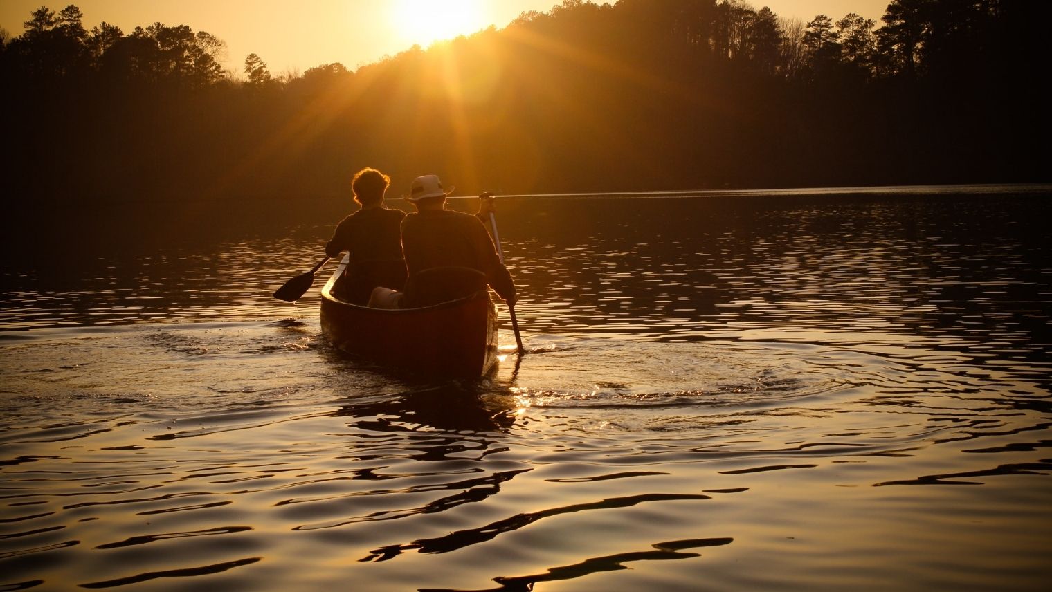 Kayakers on a lake in the low dusk sun