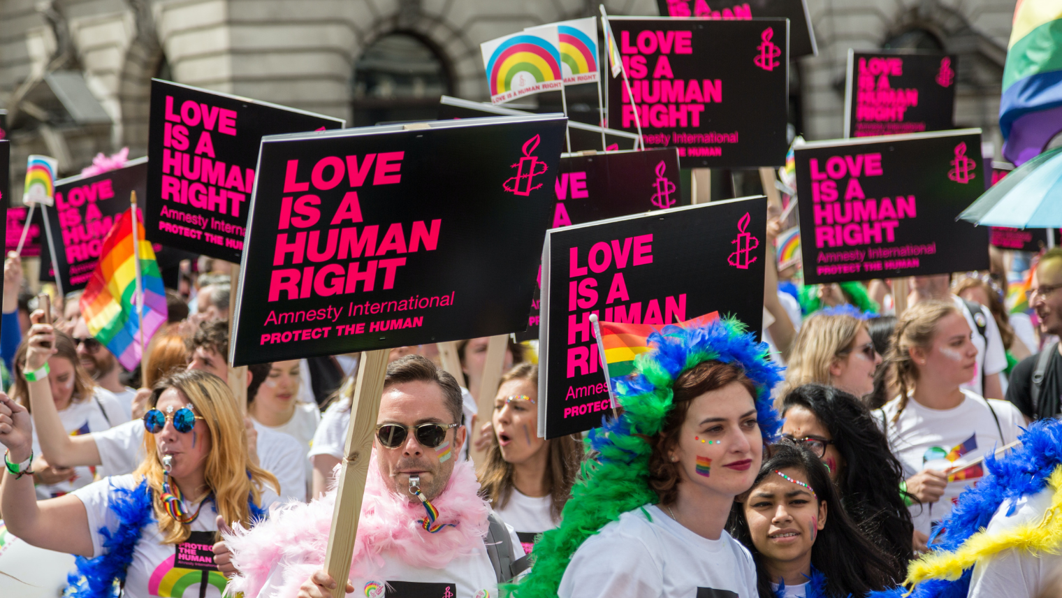 Image of a crowd at a pride event, with many holding up banners saying: 'Love is a Human Right'