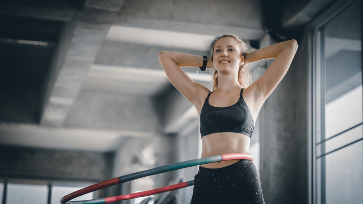 A woman in sportswear hula hooping at a studio