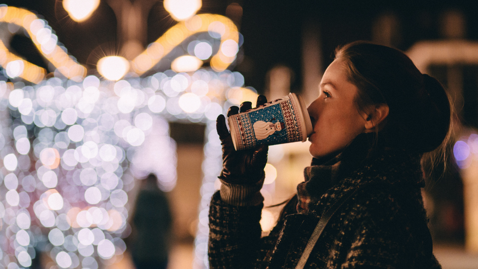 A woman drinking a hot drink at a Christmas market