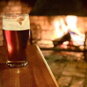 A pint of larger by a fire place