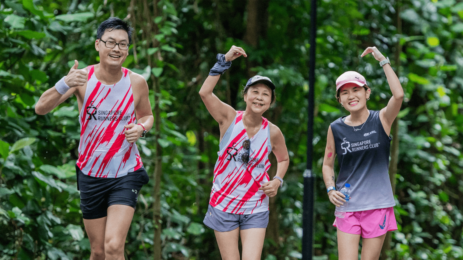Three smiling runners from the Singapore Runners Club jogging through greenery, giving thumbs‑up and cheerful gestures.