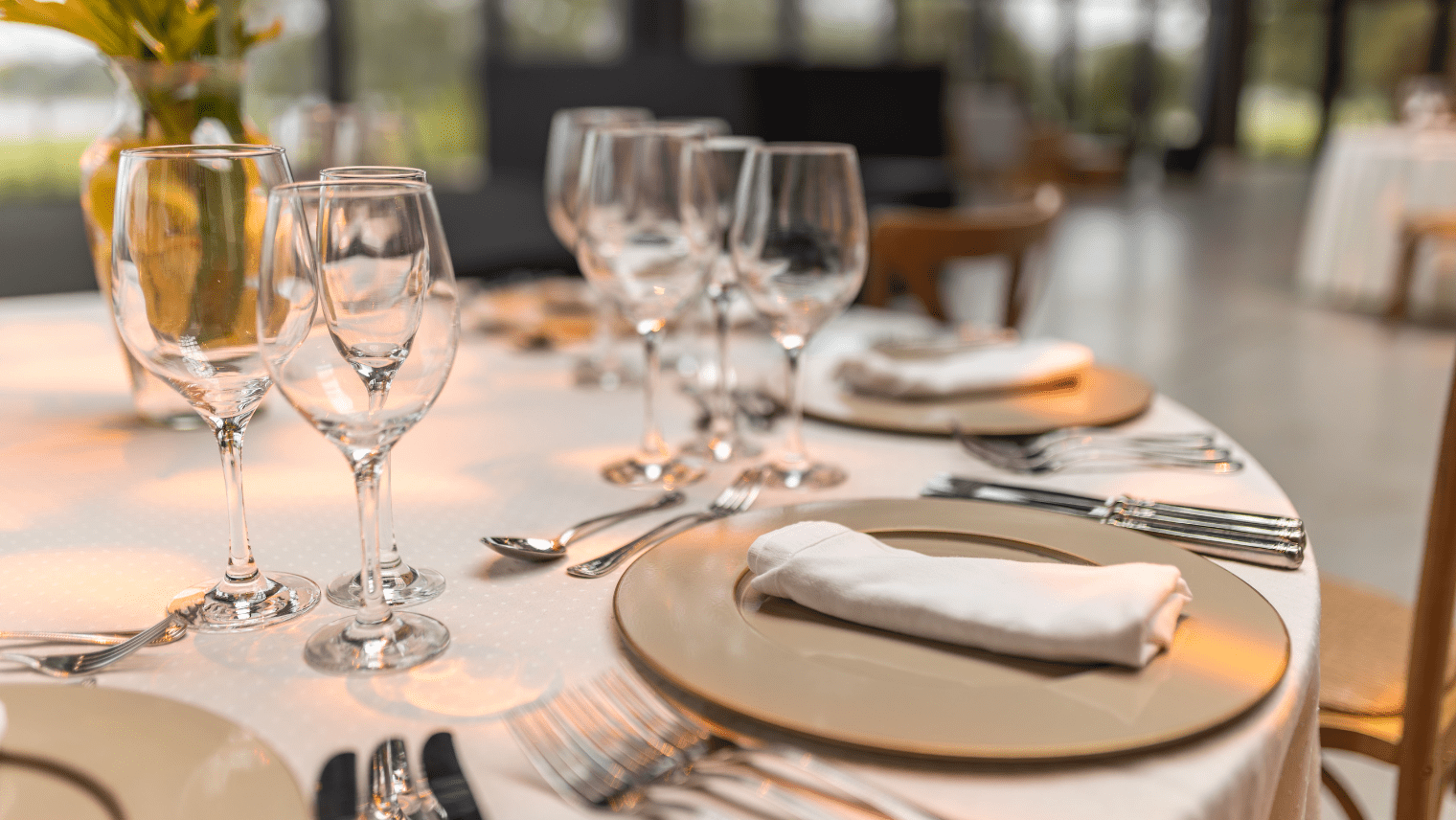 Formal table setting with gold plates, folded napkins, and glassware.