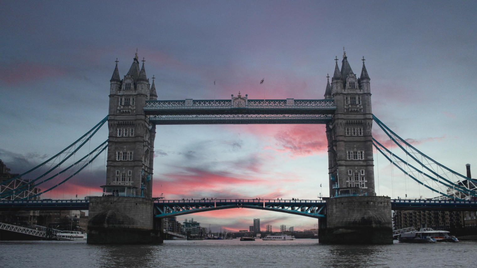 Tower Bridge at sunset with boats on the Thames.
