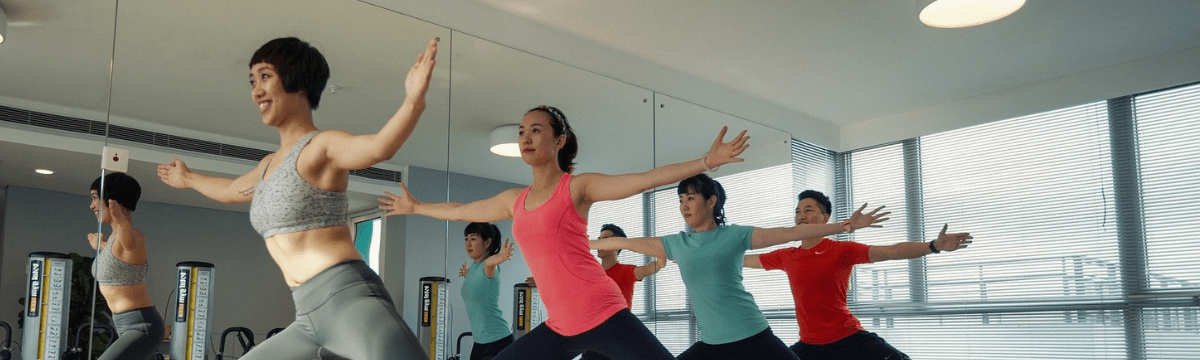 Several people engaged in a pilates class, demonstrating different poses and using exercise mats in a bright studio