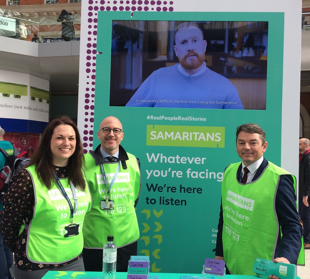Three members of South Western Railway staff standing in front of a Samaritans banner