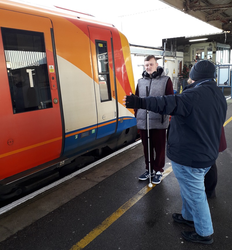 Jimmy, a visually impaired traveller, is stood next to a South Western Railway train at a station
