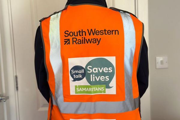 Back of a man wearing a Hi-vis tabard with South Western Railway and 'Small Talk Saves Lives' logos