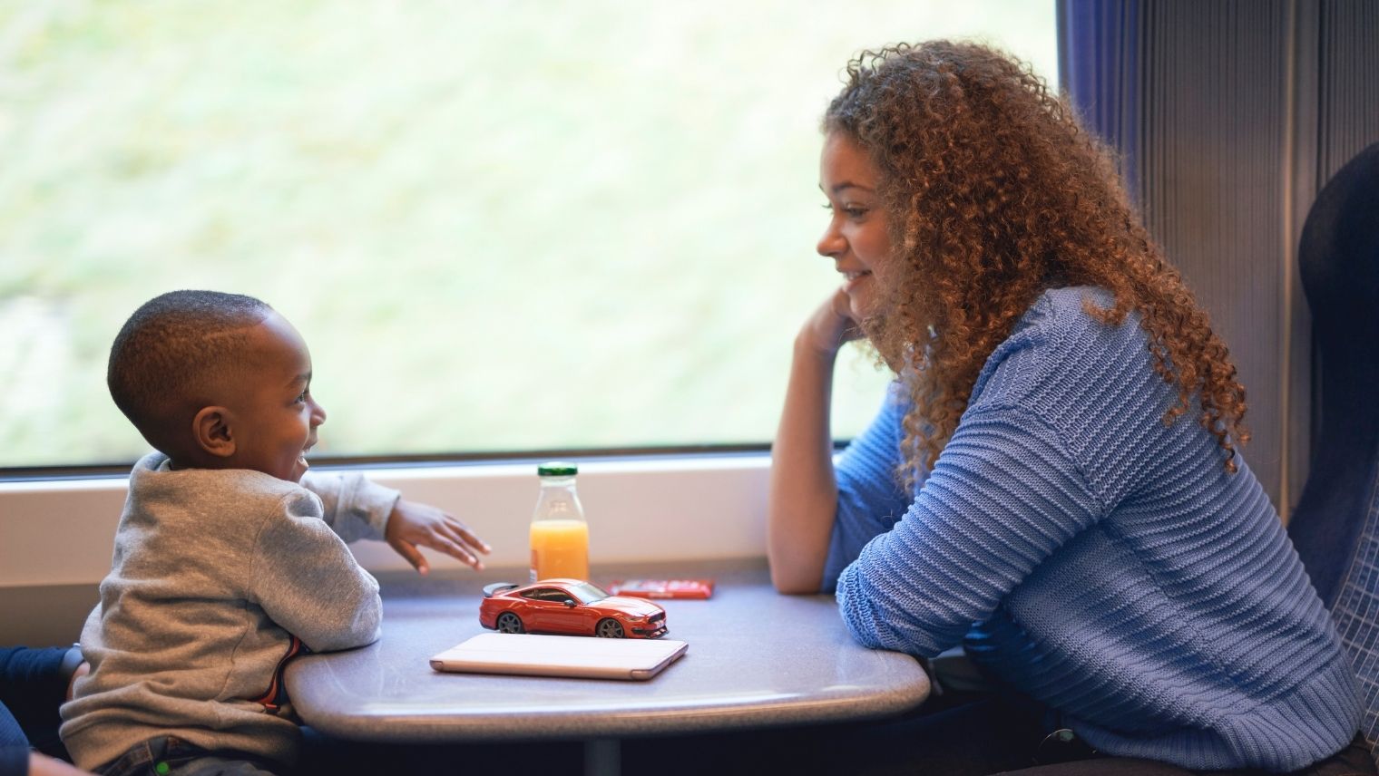 A parent and child in playful conversation on a train
