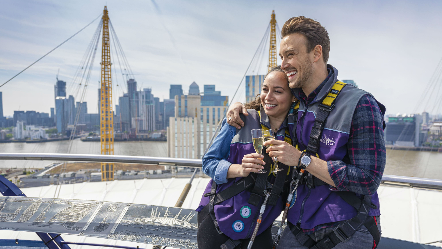 A couple enjoying a glass of champagne while stood at the top of the O2 dome