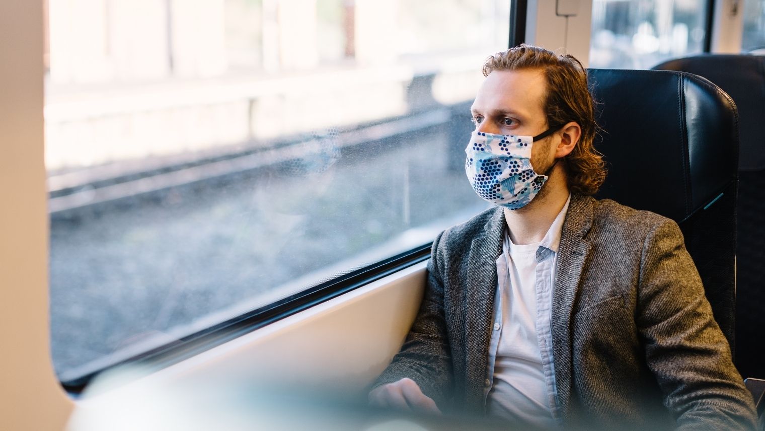 Male commuter sitting on a train and looking out of the window